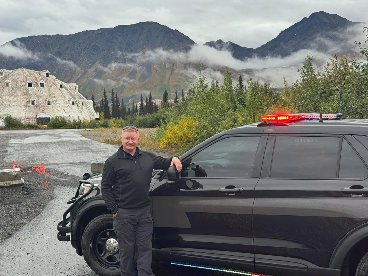 Team member with police SUV in Alaska mountains
